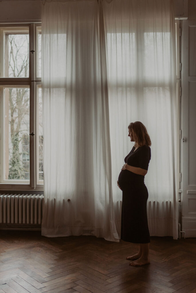 babybauchfotos in einem Tageslichtstudio in pankow in berlin mit einer wunderschönen hochschwangeren Frau mit Babybauch im 9. Monat.