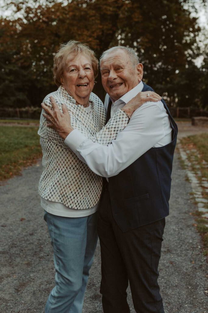 Oma und Opa couple shooting in Weißensee direkt am See. Paarfotos zum 65. Hochzeitstag mit alten Händen und Eheringen. beim spazieren gehen mit der Familie im grünen auf einer wiese.